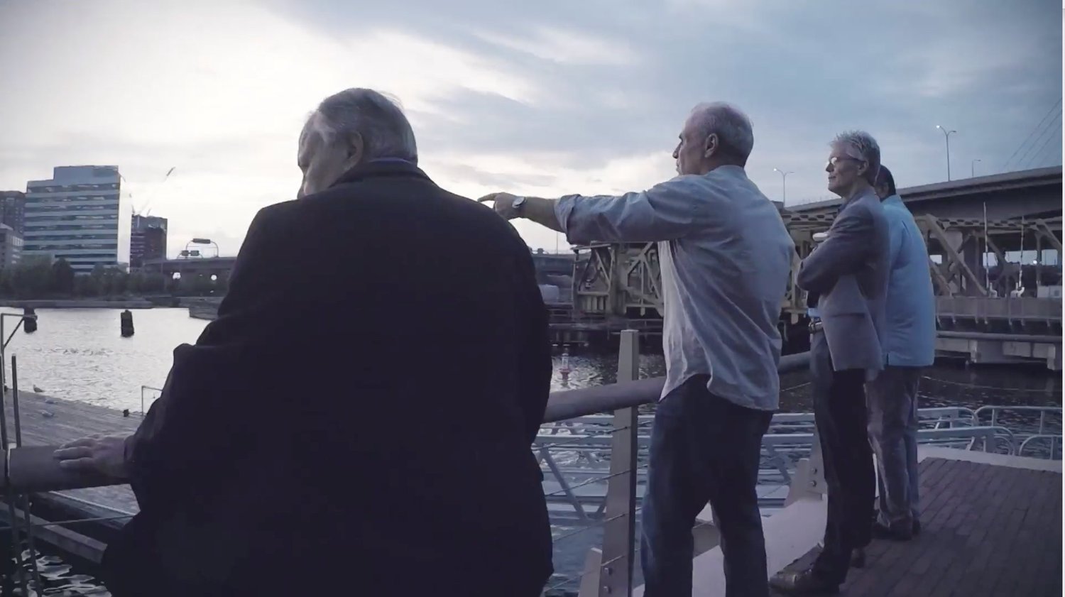 The GDI investigators standing at a river dock at dusk, one pointing out across the water